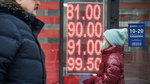 Folk går forbi et valutakontor i Moskva. Den russiske rubelen faller kraftig mandag morgen.