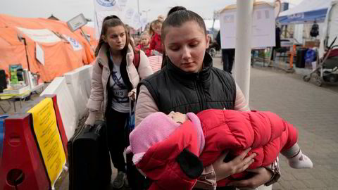 En flyktning, bærende på en baby, ankommer fra Ukraina til Polen ved grensestasjonen Medyka tirsdag.
