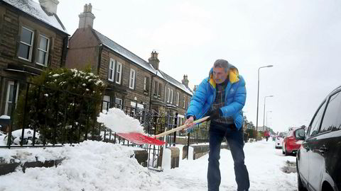 En mann spar snø utenfor sitt hjem i Portobello, Edinburgh. Snøvær og lave temperaturer har skapt problemer i hele Storbritannia, med fly som innstilles, tog som bryter sammen og passasjerer som strander i kulden i flere timer.