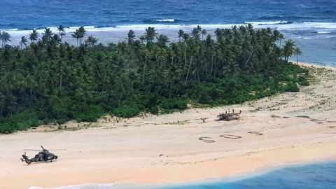 Et australsk helikopter landet på stranda der tre menn ble funnet etter å ha skriblet «SOS» i sanden.