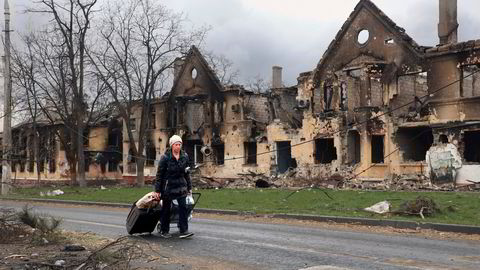 En kvinne går forbi ødelagte hus i den beleirede og istykkerbombede byen Mariupol, ved kysten lengst sør i Donbas-regionen i Ukraina. Bildet ble tatt i forrige uke i en del av byen som nå kontrolleres av prorussiske separatister.