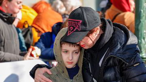 En kvinne omfavner en gutt mens de står i køen for å registrere seg som ukrainske flyktninger i Brussel.
