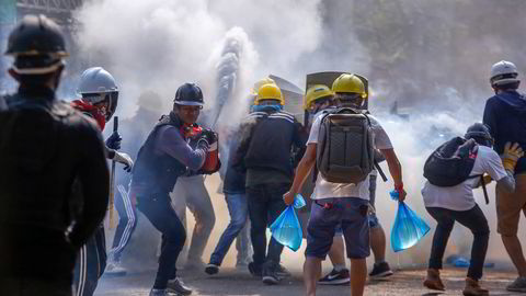 Demonstranter bruker brannslukningsapparater for å beskytte seg mot tåregass i Yangon i mars i år. Protestene var svar på kuppet i februar.