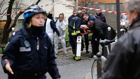 I bakgrunnen blir et av ofrene for terrorhandlingene i Charlie Hebdos kontorer den 7. januar i år fraktet bort på båre. Foto: Jacky Naegelen, Reuters/NTB Scanpix