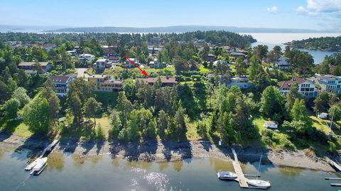 Den aktuelle eiendommen på Langodden, Snarøya (rød pil) ligger usjenert til med egen strandlinje.