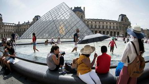 Frankrike har målt de høyeste temperaturene siden 2003. Her avkjøler turister seg ved en fontene utenfor Louvre i Paris tirsdag.