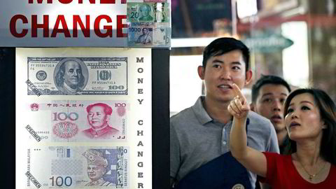 Målet er å kunne benytte yuan like enkelt i transaksjoner som amerikanske dollar og euro. Her studerer to personer en plakat med vekslingmuligheter. Foto:  Edgar Su, NTB Scanpix