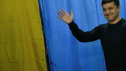 Komiker Volodimir Zelenskij vinker til fotografene på vei inn til stemmeurnen søndag.
