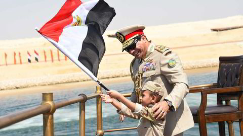 Egypts president Abdel-Fattah el-Sissi smiler sammen med en uniformskledd gutt, under åpningen av den nye Suez-kanalen i dag, torsdag.