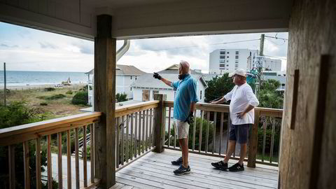 Phil Gillespie (til venstre) og Neil Hyman ser fra terrassen at livvakttårnene på stranden blir demontert. Selv har de har dekket til alle vinduene og skal snart reise.
