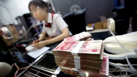 KINA: Kinesiske Yuan-sedler ligger ved skranken mens en ansatt i the Industrial and Commercial Bank of China Ltd (ICBC) snakker med en kunde. Foto: Carlos Barria/Reuters/NTB scanpix