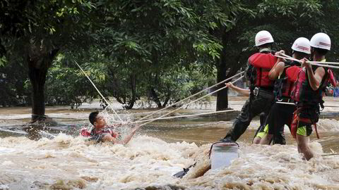 Havnivået i verden stiger i stadig raskere takt. På bildet hjelper redningsmannskaper en mann som er fanget av vannmassene etter at vannivået i elven Lijiang i Kina plutselig steg kraftig. Foto: Stringer/Reuters/NTB scanpix