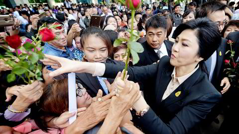Thailands tidligere statsminister Yingluck Shinawatra mottar roser fra sine tilhengere på vei inn i retten i Bangkok tirsdag. Foto: Pornchai Kittiwongsakul, AFP/NTB Scanpix