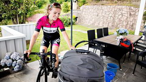 Heidi Sandstø (33) benytter sykkelrulle på terrassen når hun trener hjemme. Sønnen koser seg i vognen ved siden av. Foto: Marte Christensen ​