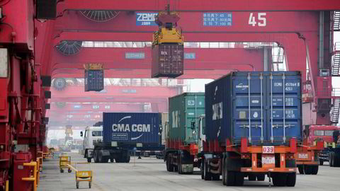 Lastebiler flytter shipping-containere i havnebyen Qingdao i Shandong-provinsen i østre Kina. Foto: Chinatopix via AP Photo/NTB scanpix