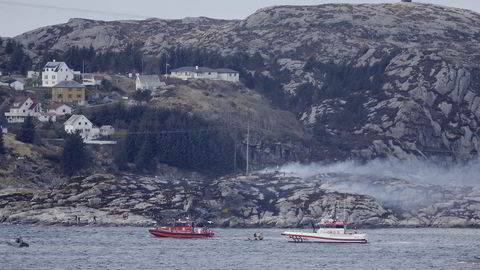 Redningsmannskaper i sjøen ved ulykkesstedet. Røyk fra det havarerte helikopteret i bakgrunnen. Foto: