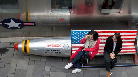 Kina protesterer mot USAs nye straffetoll. Her to kvinner på en benk med amerikansk flagg ved en amerikansk klesbutikk i Beijing.