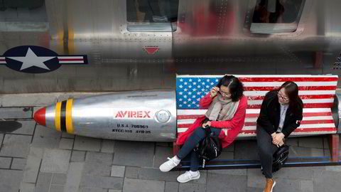 Kina protesterer mot USAs nye straffetoll. Her to kvinner på en benk med amerikansk flagg ved en amerikansk klesbutikk i Beijing.