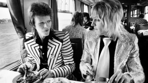 Smakte ertene?. David Bowie og bandmedlem Mick Ronson inntar en solid britisk toglunsj på vei fra London til Ziggy Stardust-konsert i Aberdeen i 1973. Mick Rock var med på hele turneen, som Bowies offisielle fotograf. – De ser ut som om de kommer fra en annen planet, minnes han. Foto: © Mick Rock 2015