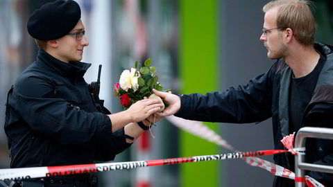 En fotgjenger gir blomster til en politimann, så han kan legge dem på åstedet i München. Foto: REUTERS/Michael Dalder