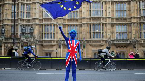 En antibrexitdemonstrant kledd i det britiske flagget vifter med et EU-flagg foran Parlamentet i London.