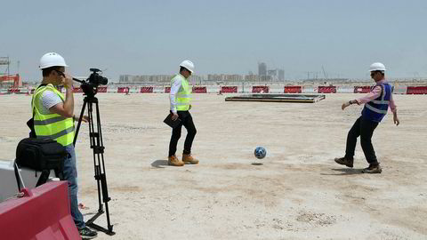Byggeleder Tamim Loutfi Elabed (til høyre) sparker en fotball på grunnen hvor Lusail-stadionet med 80.000 seter skal bygges i anledning fotball-VM i Qatar i 2022. Landet har fått mye kritikk for vilkårene som tilbys fremmedarbeiderne på byggeplassene.