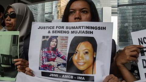 En arbeidsinnvandrer holder opp en plakat med bilder av Sumarti Ningsih (t.v.) and Seneng Mujiasih, som ble torturert og drept av den tidligere Merrill Lynch-ansatte Rurik Jutting. Foto: AFP/Anthony Wallace