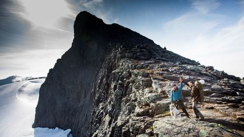 Toppen av Storsylen ruver i bakgrunnen mens  Anders Helstrup (til venstre), kompisen Jan Arne Janssen og hunden Obelix markerer at de har nådd et av turens delmål. Her har de krysset Norge fra havet på Vestlandet til grensen mot Sverige i Midt-Norge.