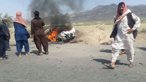 Pakistanske innbyggere samles rundt vrakrestene til Taliban-lederens bil som ble bombet av amerikanske droner. Foto: AFP/NTB Scanpix