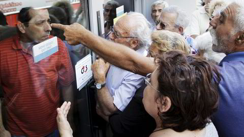 Mandag stengte greske banker. Her krangler pensjonister i Aten med en bankansatt for å få ut pensjonspengene sine. Foto: Stafanos Rapanis, Reuters/NTB Scanpix