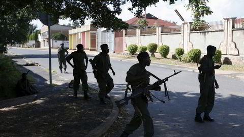 Regjeringssoldater foran en opprørssoldat som ligger såret eller drept i en gate i Burundis hovedstad Bujumbura torsdag. Foto: