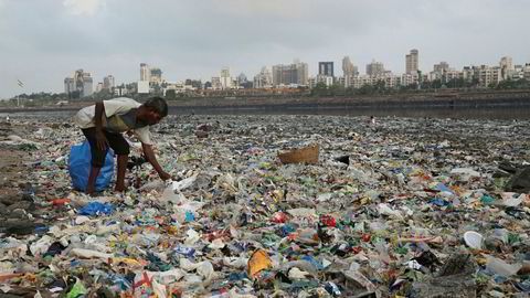 En mann samler inn plast og andre resirkulerbare materialer fra stranda langs Arabiahavet i Mumbai i India.