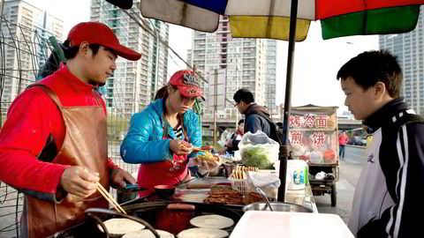 Den «nye økonomien» i Kina med tjenesteytende sektor og privat forbruk vokser. På bildet forbereder en gateselger mat til en kunde i Beijing. Foto: Nicolas Asfouri/AFP Photo