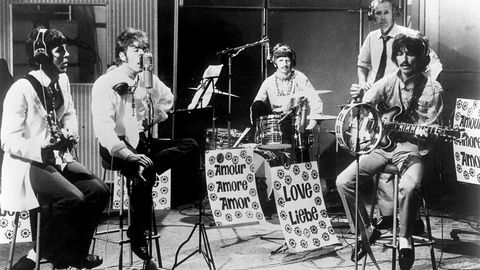 Fire pluss én. The Beatles – det vil si Paul McCartney (f.v.), John Lennon, Ringo Starr og George Harrison – spiller «All You Need is Love» i London i 1967. George Martin (med slips) følger med.