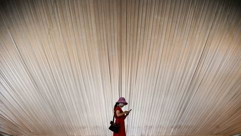 En kvinne ser på mobiltelefonen sin, mens hun vandrer rundt på et utstillingssenter i Shanghai, Kina. Smarttelefonsalget i første kvartal falt med hele 21 prosent sammenlignet med foregående kvartal.