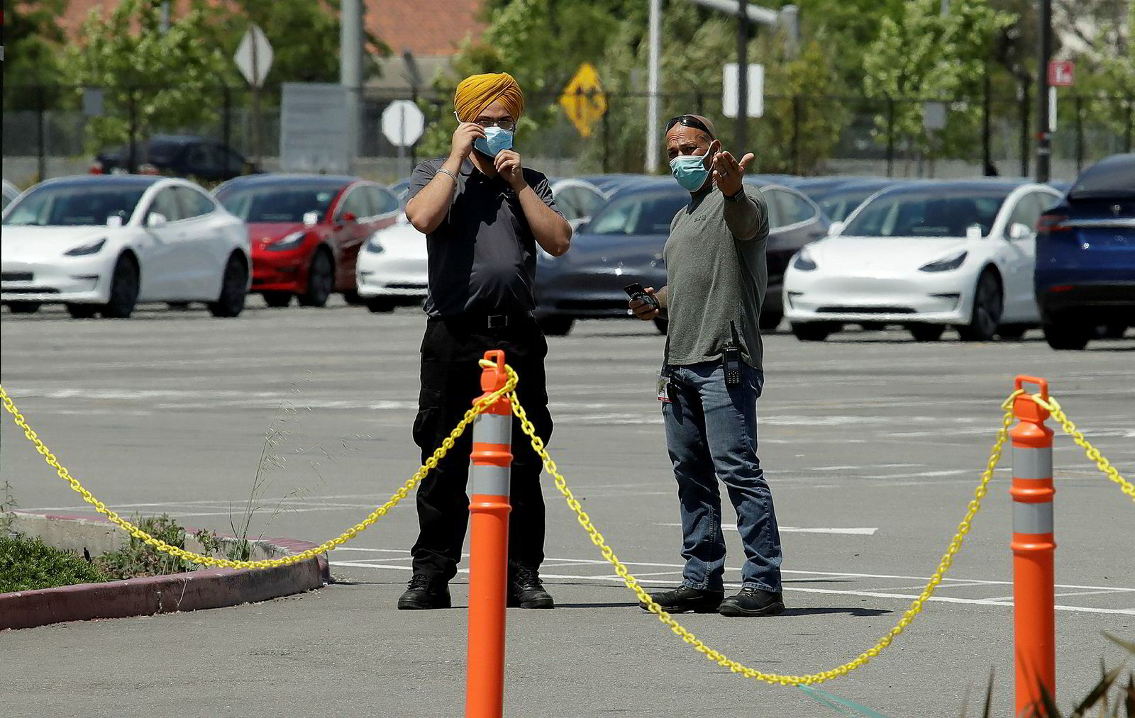 Masked guards snap the new Tesla out of the Fremont plant on Monday. According to Elon Musk himself, production is underway, despite the government's ban.