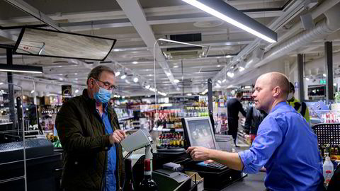 Vinmonopolet er blant dem som nå opplever en ny shoppingboom. Butikksjef Jetmund Ringstad har merket at folk kjøper dyrere viner. Her ekspederer han kunde Dag Leren.