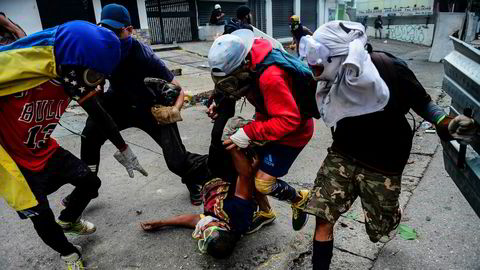 Opposisjonelle demonstranter forsøker å hjelpe en skadet venn etter sammenstøt med politiet.