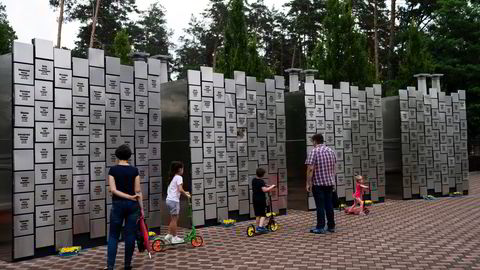 En ukrainsk familie besøker en minnevegg for alle drepte som russiske styrker sto bak i Butsja.