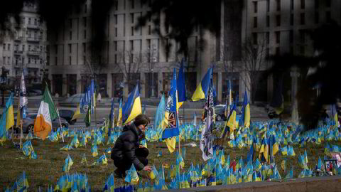 En kvinne setter ned flagg ved et minnesmerke for falne ukrainske soldater i Kyiv.