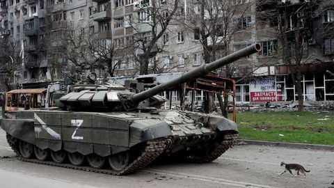 En katt spaserer foran en russisk stridsvogn i svært ødelagte Mariupol sør i Ukraina.