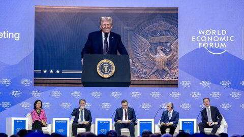 Donald Trump på skjermen over scenen i Davos, der toppsjefene sitter Banco Santander, Bank of America, TotalEnergies, Blackstone og moderator Børge Brende.