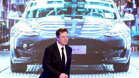 Tesla-sjef Elon Musk gående foran en skjerm med bilde av Tesla Model 3 under en åpningsseremoni for Tesla Model Y i januar 2020.