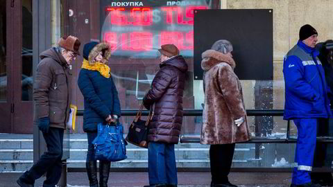 Den russiske økonomien kommer til å gå inn i en resesjon, ifølge valutastrateg Magne Østnor. Her står mennesker og venter på bussen foran en valutaveksler i Russlands hovedstad Moskva.