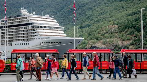 Cruiseturisme er stor business i Flåm. Her er en gruppe turister foran et cruiseskip og et turisttog i Flåm.