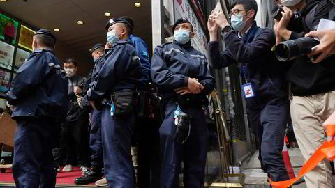 Politiet hoder vakt mens journalister tar bilder utenfor bygningen der Stand News har kontor i Hongkong.