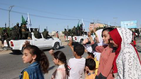 Palestinere i Gaza vinker til den væpnede delen av Hamas, Al-Qassam brigadene, under en militærparade i byen Khan Yunis torsdag.