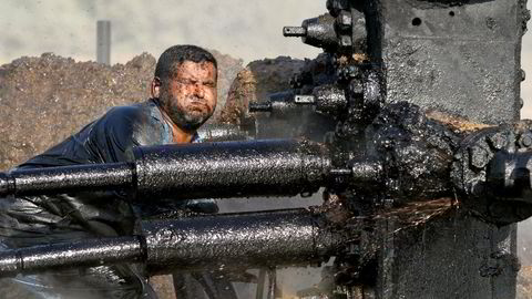 IEA oppjusterer estimatene for både etterspørsel og tilbud neste år. Avbildet er en irakisk oljearbeider som prøver å reparere en pumpe på en oljebrønn i Bob Al-Sham, Irak.