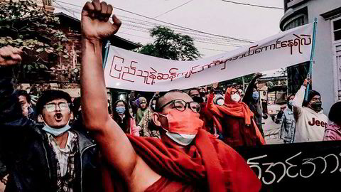En buddhistisk munk hever den knyttede neven mens han marsjerte under et protestmøte mot militæret etter kuppet i Myanmar i fjor. Telenor-kunder i Myanmar som er regimekritikere frykter konsekvenser ved et salg av mobilvirksomheten.