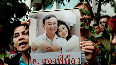 Bildet, som ble tatt i august, viser en kvinne som holder opp et bilde av Thailands tidligere statsminister Yingluck Shinawatra og broren Thaksin Shinawatra.